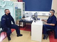 Komendant Powiatowy Policji w Pabianicach siedzi na przeciwko lekarza.