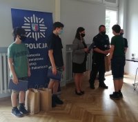 Komendant Powiatowy Policji w Pabianicach wraz z wicestarostą powiatu pabianickiego wręczają nagrody laureatom konkursu profilaktycznego.