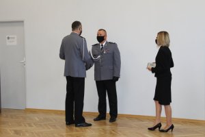 podinspektor Mariusz Siejka gratuluje inspektorowi Jarosławowi Tokarskiemu. Obok znajduje się nieumundurowana kobieta.