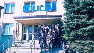 Grupa uczniów stoi na schodach wejściowych do budynku Policji.