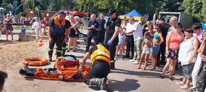 Grupa osób ogląda akcję ratunkową reanimowanego mężczyzny wyciągniętego z wody.