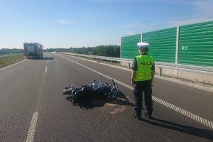 Miejsce wypadku, policjantka prowadzi  oględziny rozbitego motocykla.