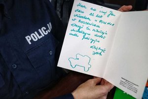 Otwarta kartka z życzeniami do Świętego Mikołaja trzymana przez umundurowaną policjantkę.