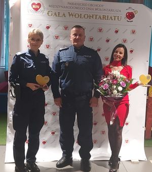 Z lewej strony stoi policjantka uhonorowana złotym sercem, w środku znajduje się Komendant Powiatowy Policji w Pabianicach a z prawej strony stoi prezes Fundacji Pomaganie jest Fajne.