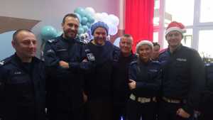 Komendanci z pabianickiej jednostki Policji, funkcjonariuszka i funkcjonariusz pozują do wspólnego zdjęcia z aktorem Tomaszem Karolakiem.