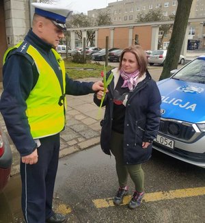 Policjant Wydziału Ruchu Drogowego Komendy Powiatowej Policji w Pabianicach obdarowuje pieszą tulipanem.
