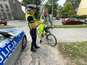 Policjantka wręcza rowerzyście kamizelkę odblaskową.