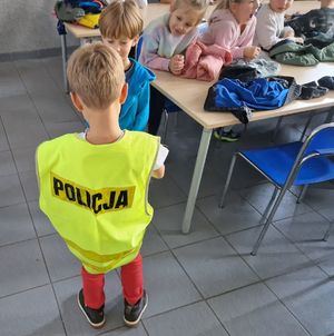 Chłopiec w kamizelce odblaskowej z napisem Policja.