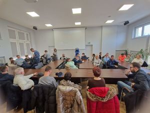 Grupa gości zebranych na auli w Komendzie Powiatowej Policji w Pabianicach. W tle widać maskotę łódzkiej Policji Komisarza Błyska.