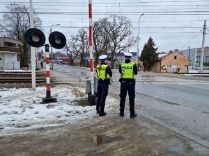 Policjanci z pabianickiej drogówki stoją na przejeździe kolejowo-drogowym.
