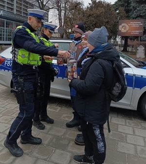 Policjant i policjantka wrzucają pieniądze do puszki Wielkiej Orkiestry Świątecznej Pomocy.