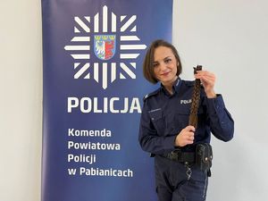 Policjantka w krótkich włosach trzyma warkocze.