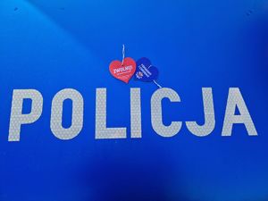 Na niebieskim tle napis policja i dwie zapachowe zawieszki w kształcie serca.