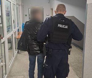 Zatrzymana kobieta stoi obok umundurowanego policjanta.