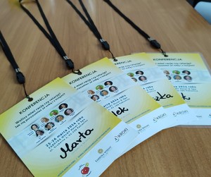 Cztery żółte  identyfikatory umożliwiające wejście na konferencję.