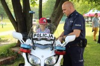 dziewczynka siedząca na policyjnym motocyklu, obok policjant