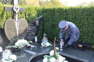 komendant powiatowy policji zapala znicz na grobie poległego na służbie funckjonariusza