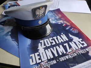 Czapka policyjna, leżąca na plakatach promujących służbę w Policji.