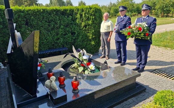 Policjanci stoją przy mogile zmarłego wraz z jego ojcem.