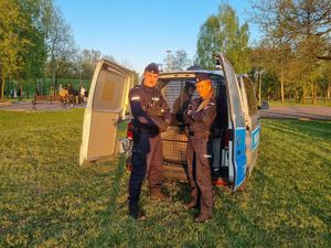Policjanci stojący przy oznakowanym radiowozie na planie filmu profilaktycznego.
