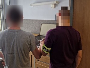 Nieumundurowany policjant pobiera odciski palców od zatrzymanego mężczyzny.
