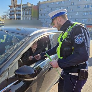 Policjant wręcza kierującej upominek.