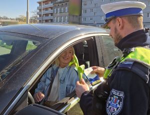 Policjant wręcza kierującej upominek.