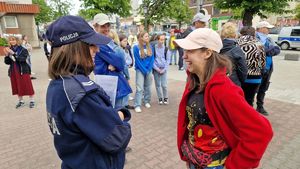 Policjantka i wolontariuszka uśmiechają się do siebie, za nimi stoją uczestnicy gry miejskiej.