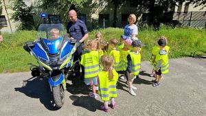 Dziecko siedzi na motocyklu, obok stoi policjant i reszta przedszkolaków.