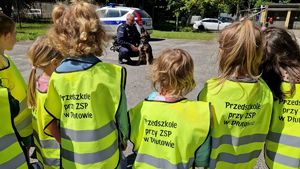 Przedszkolaki słuchają opowieści przewodnika, który znajduje się naprzeciwko nich wraz ze swoim czworonogiem.