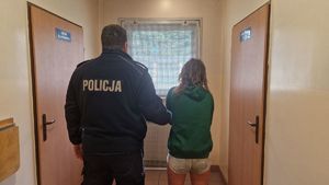 Policjant stoi z zatrzymaną kobietą.