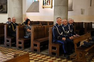 Policjanci siedzący w ławkach w kościele podczas nabożeństwa.