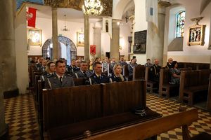 Policjanci siedzący w ławkach w kościele podczas nabożeństwa.