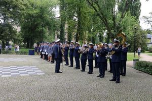 Orkiestra grająca na instrumentach. W tle widać policjantów, pracowników cywilnych i gości.