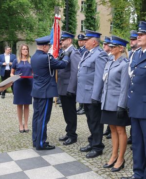 Komendant przypina medal policjantowi stojącemu w pododdziale.