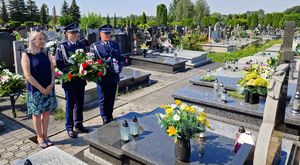 Policjanci stoją z kobietą przy grobie zmarłego funkcjonariusza.