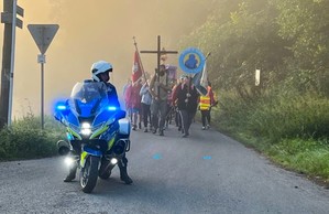 Policjant na motocyklu a za nim pielgrzymi.