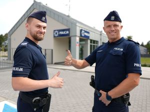 Dwóch policjantów stojących na tle posterunku policji.