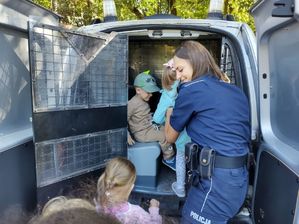 Policjantka wsadza dzieci do radiowozu.