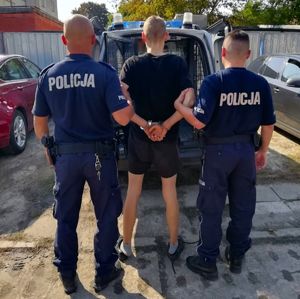 Zatrzymany mężczyzna stoi z dwoma umundurowanymi policjantami.