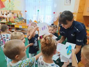 Dzieci dają policjantce namalowane obrazki.