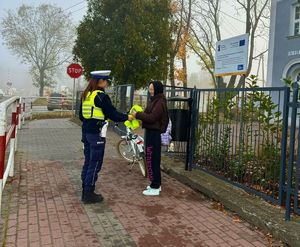 Policjantka wręcza nastolatce kamizelkę odblaskową.