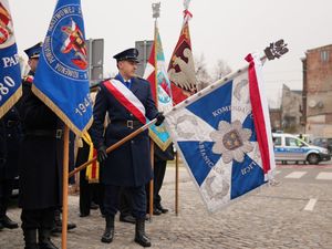 Policjant trzymający opuszczony poczet sztandarowy.