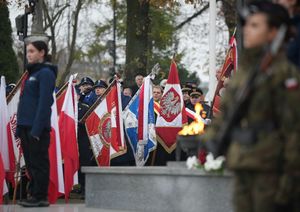 Na pierwszym planie żołnierz, w tle harcerz wraz z policjantami.