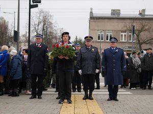 Komendant policji, komendant straży pożarnej i harcerz składają kwiaty.