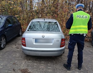 Policjant wykonujący oględziny samochodu.