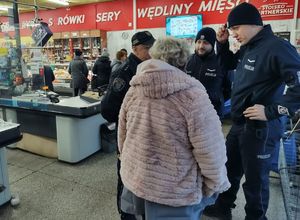 Funkcjonariusze stoją w sklepie i rozmawiają z klientką. W tle widać sklepowy asortyment.