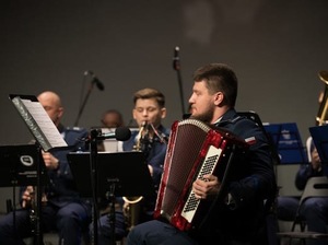 Umundurowani policjanci z orkiestry, grający na instrumentach.