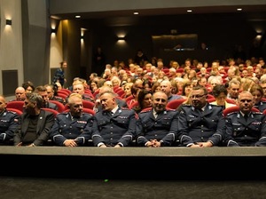 Widownia, na której w pierwszym rzędzie siedzą umundurowani policjanci, a za nimi publiczność zgromadzona na koncercie.