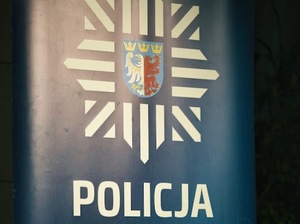 Na granatowym tle logo pabianickiej policji, a pod nim napis: Policja.